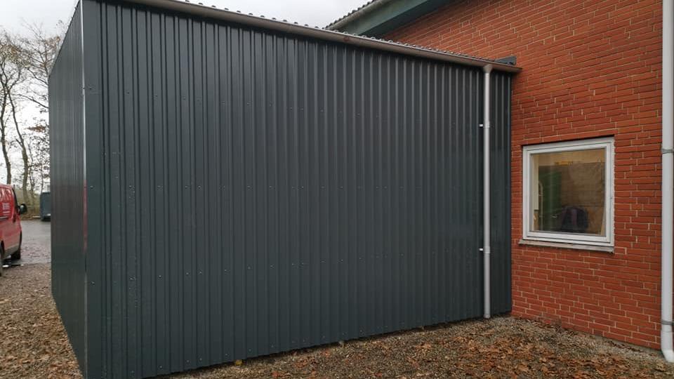 En moderne, grå metalbygning tilføjet til en rød murstensbygning med et vindue.
