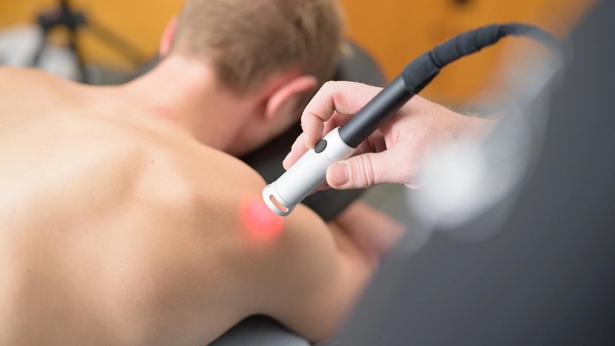 En person får laserbehandling på ryggen med en håndholdt laser enhed.