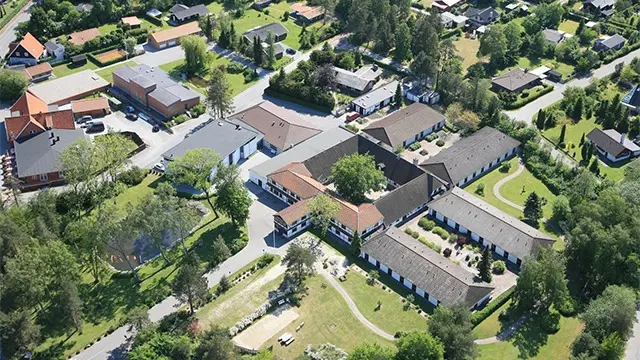 Luftfoto af en landsby med huse, veje og grønne områder, der viser et roligt boligområde.