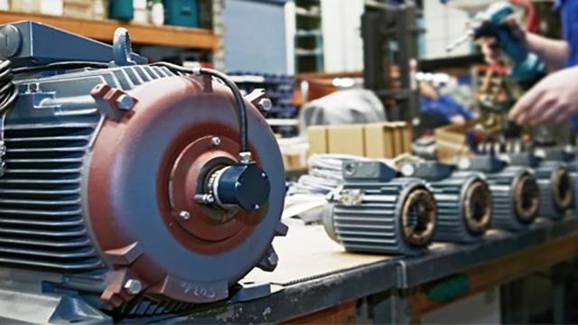En nærbillede af en elektrisk motor på et værksted med flere motorer i baggrunden.