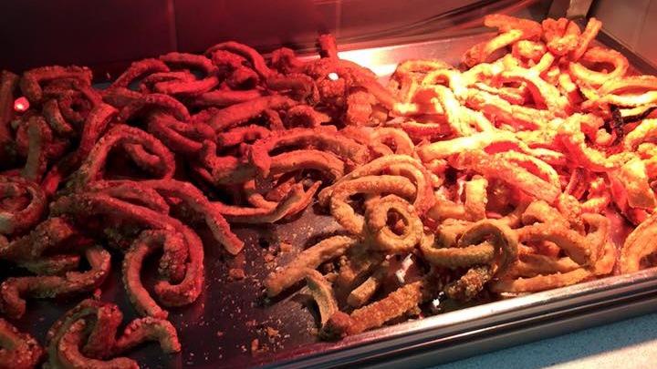 Friturestegte snacks i en varm buffet, gyldne og sprøde, dækket med krydderier og salt.