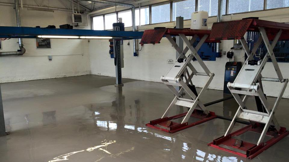 Et bilværksted med to hydrauliske lifte og en ny, glat gulvbelægning. Værkstedet er lyst og rummeligt.
