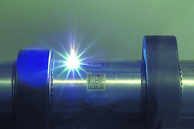 Lasergravering på metalrør med tydelig QR-kode og lysrefleksion.