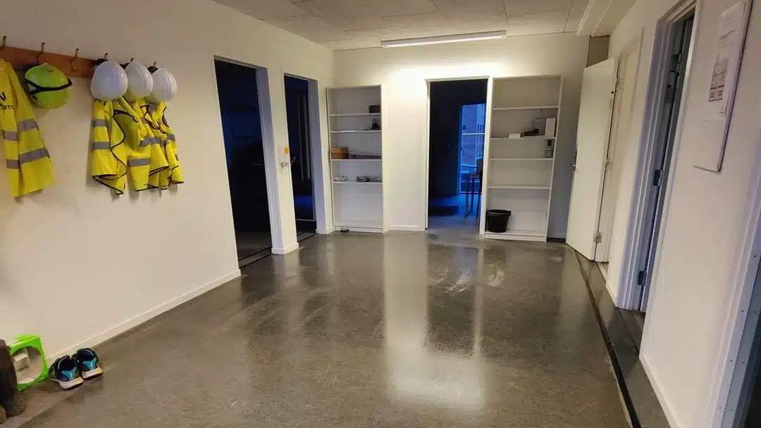 Et rum med glatte gulve, opbevaringsskabe og sikkerhedstøj hængende på væggen.