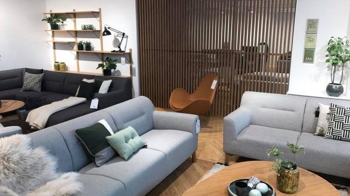 Moderne stue med grå sofaer, træhylder, planter og en rund bord med dekorationer.