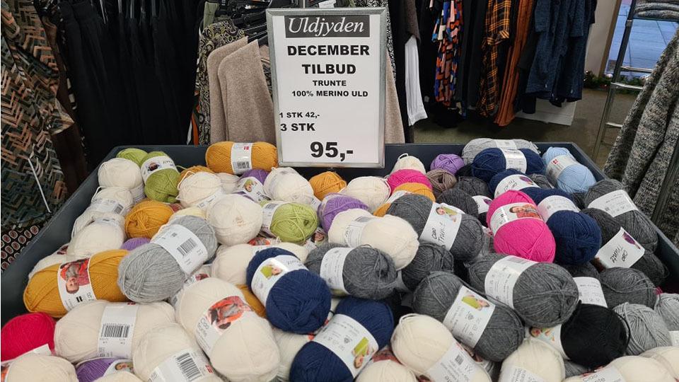 Uldgarn i forskellige farver og kvaliteter i en butik med et skilt om decembertilbud til 95 kr. for 3 stk.
