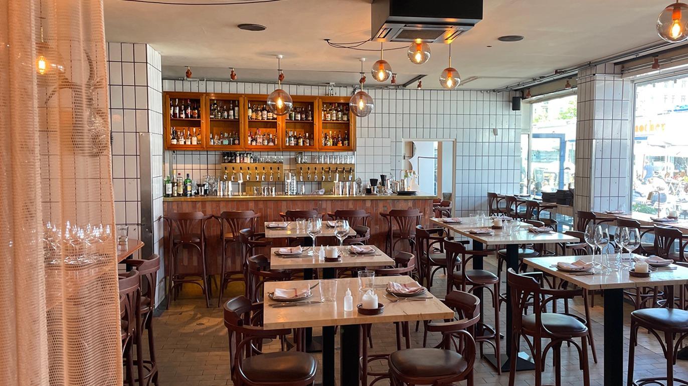 Moderne restaurant med træmøbler, barområde og borddækning i en lys og indbydende atmosfære.
