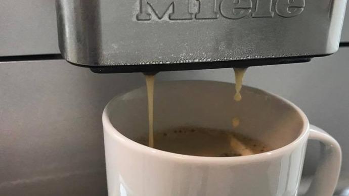 Kaffe der brygges fra en Miele kaffemaskine ned i en hvid kop.