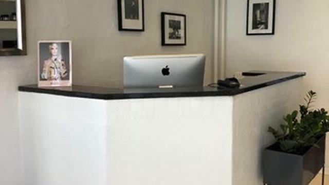 Modtagelsesområde med en computer, planter og billeder på væggen.