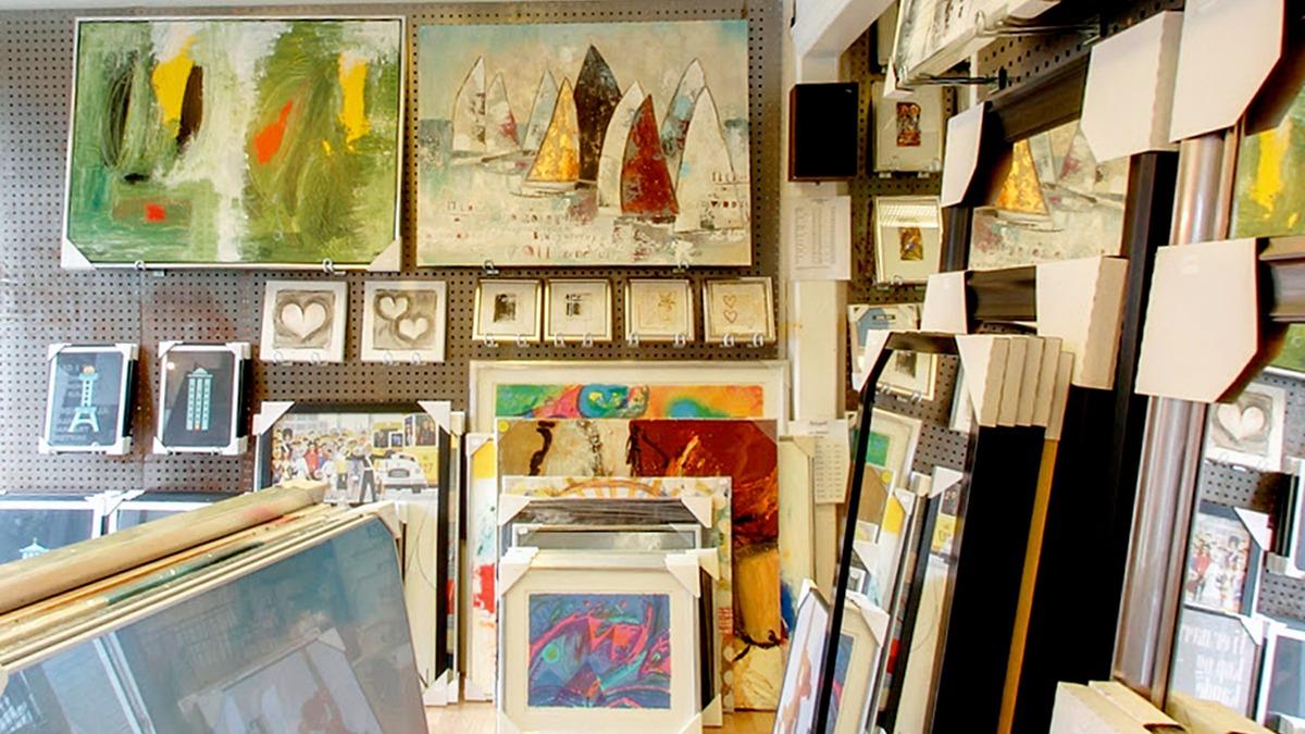 Et kunstgalleri med malerier, rammer og kunstværker på væggene og i forgrunden.