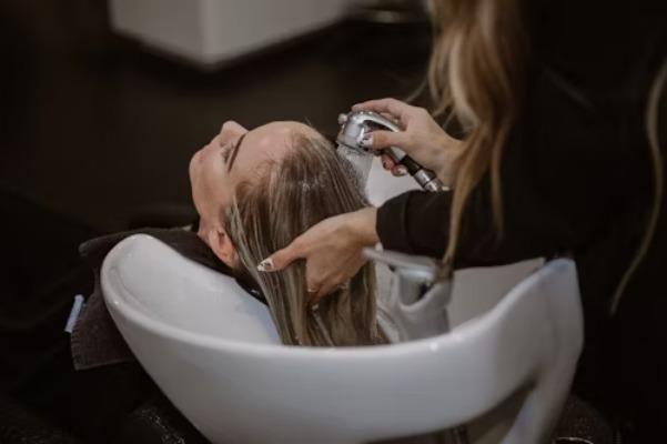 En kvinde får vasket sit hår i en frisørsalon, mens en frisør masserer hendes hoved.