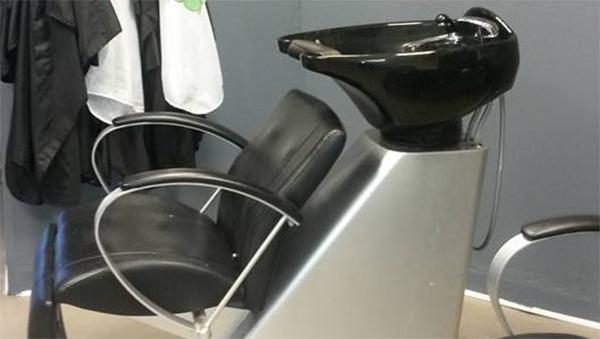 En moderne frisørstol med en sort vask i en frisørsalon.