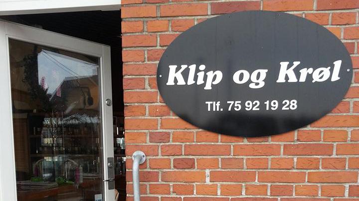 Klip og Krøl frisørsalon med sort skilt på murstensvæg og indgangsdør.