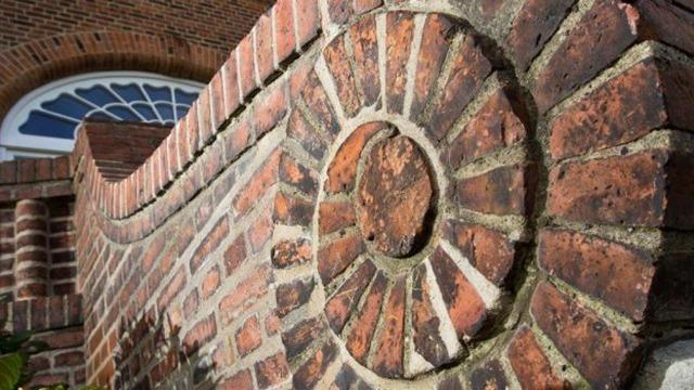 Detalje af en mur med spiralformet murværk og runde mursten, der viser håndværkets skønhed.