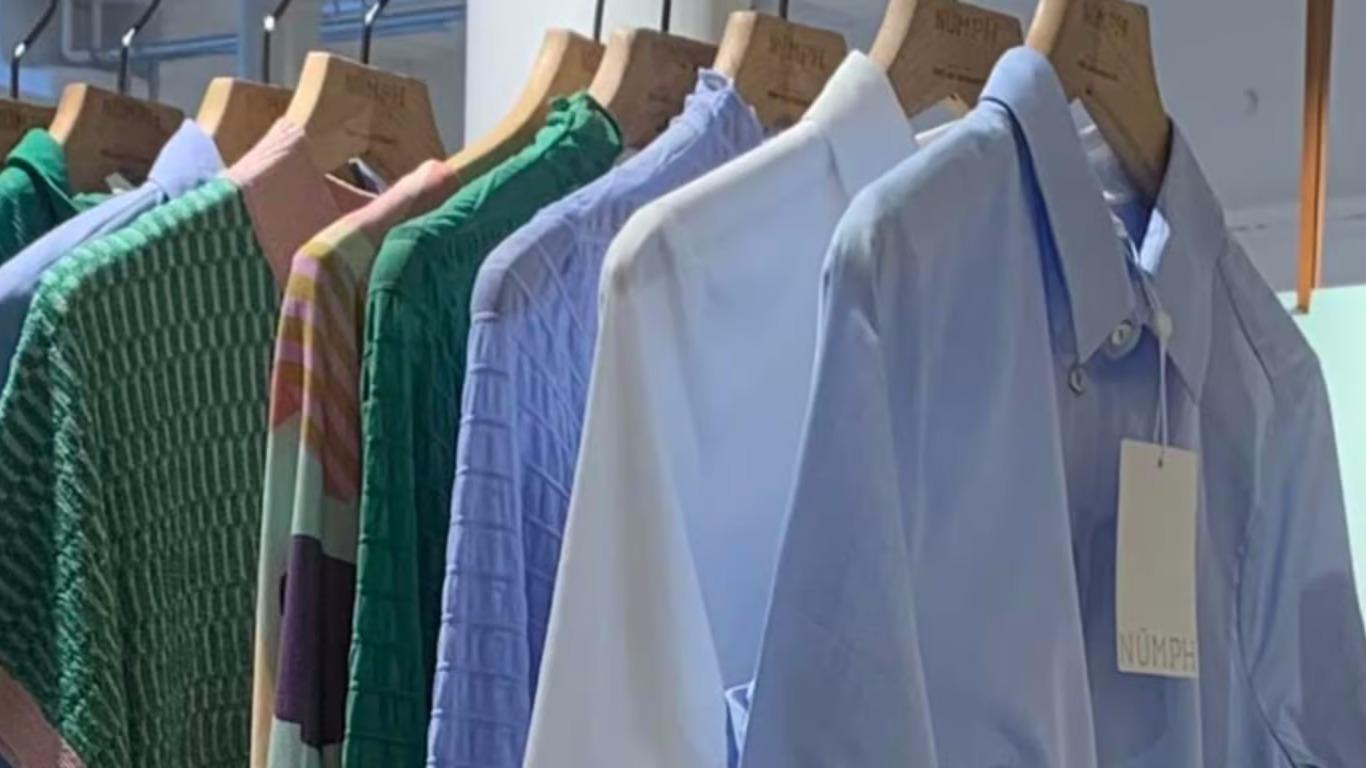 En række farverige skjorter hængende på bøjler i en butik.