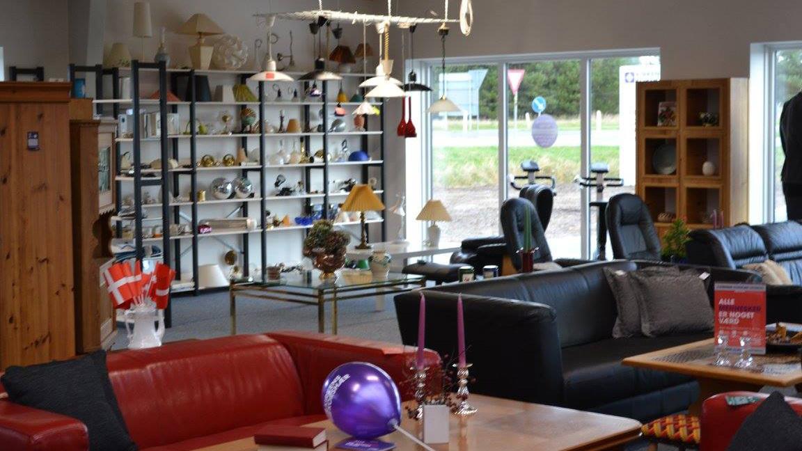 Indendørs udsigt af en møbelforretning med sofaer, lamper og dekorative genstande på hylder.