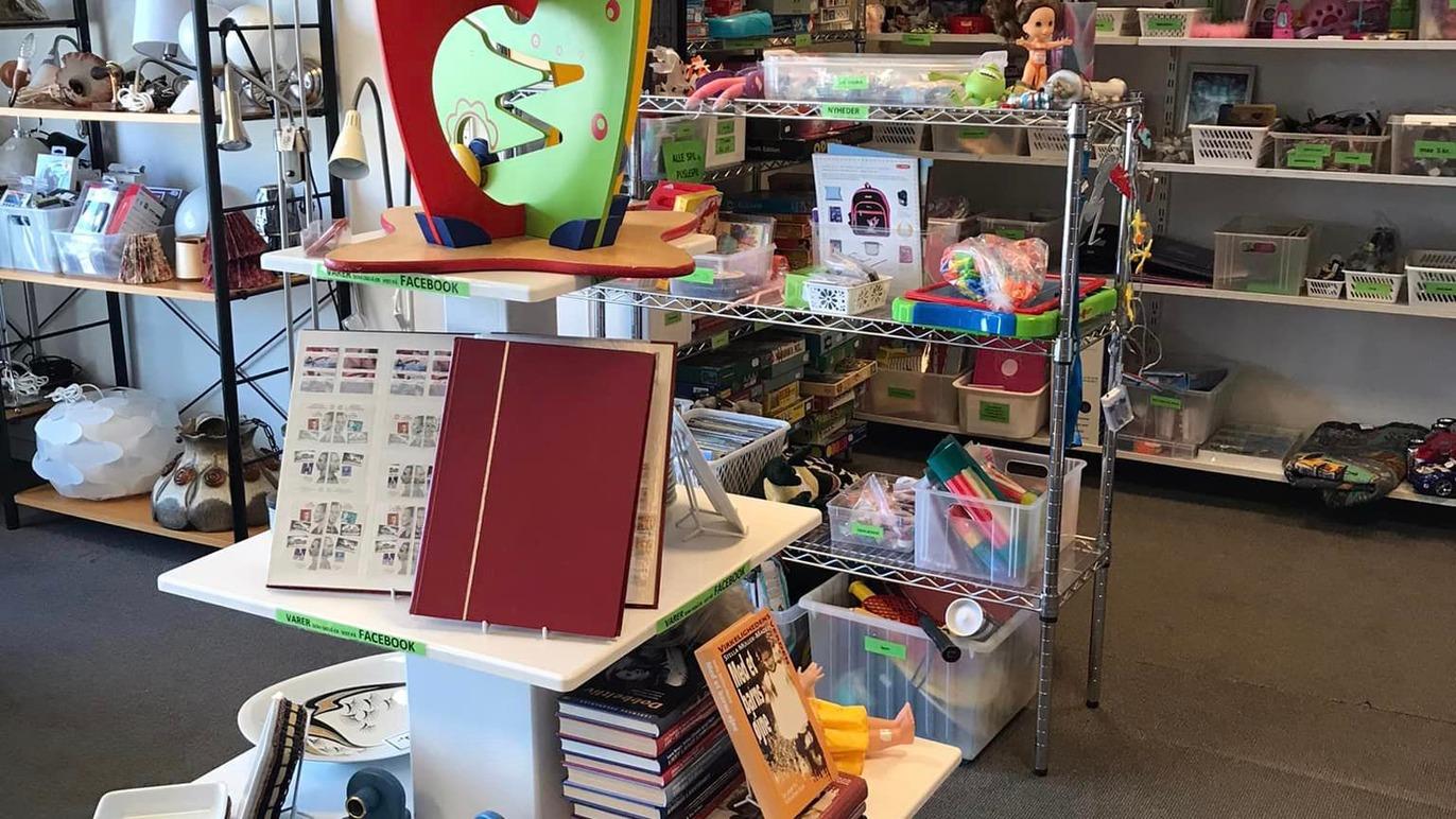 En farverig legetøjsudstilling med bøger, spil og forskellige børneartikler i en genbrugsbutik.
