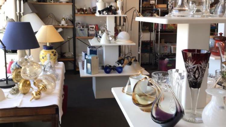 En butik med forskellige glasvarer, lamper og dekorationer på hylder og borde.