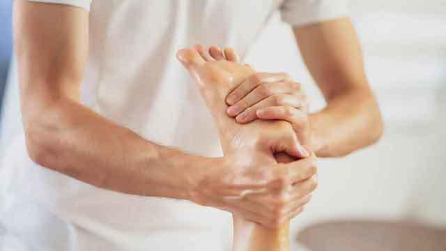En person får fodmassage med hænderne i et lyst rum.