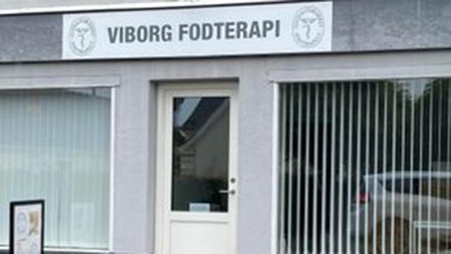 Viborg Fodterapi facade med vinduer og skilt, der viser fodterapi-tjenester i en by.