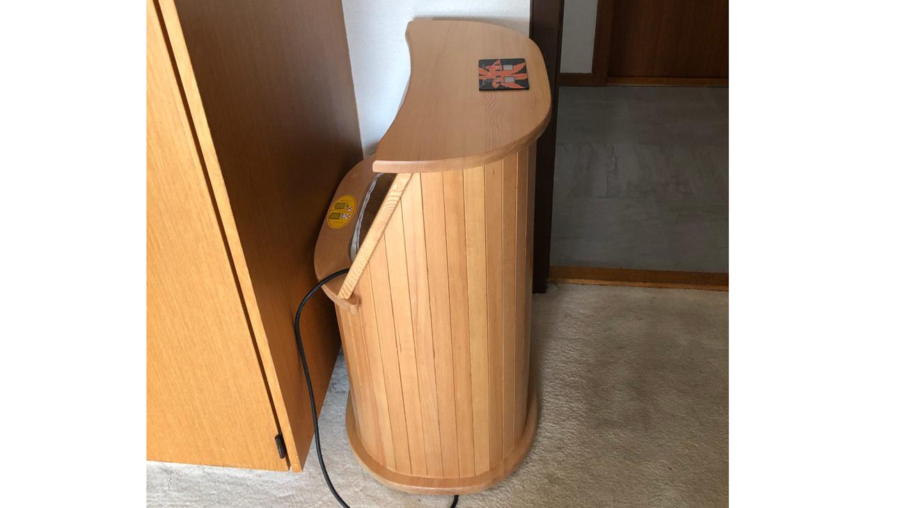 En træ sauna med en buet form, placeret i et rum med trævægge og et tæppe.