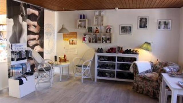 Indretning af en hyggelig salon med stole, hylder med sko og billeder på væggene.