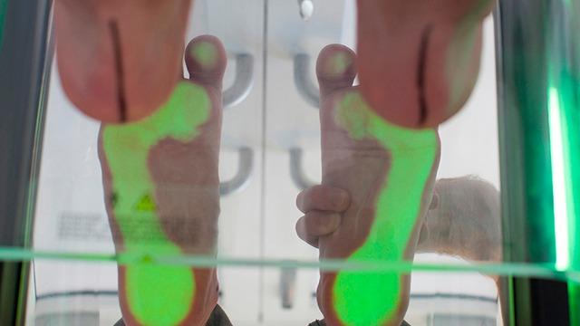 Billede af en person, der står på en scanner, der viser fodaftryk med grønne og røde områder.