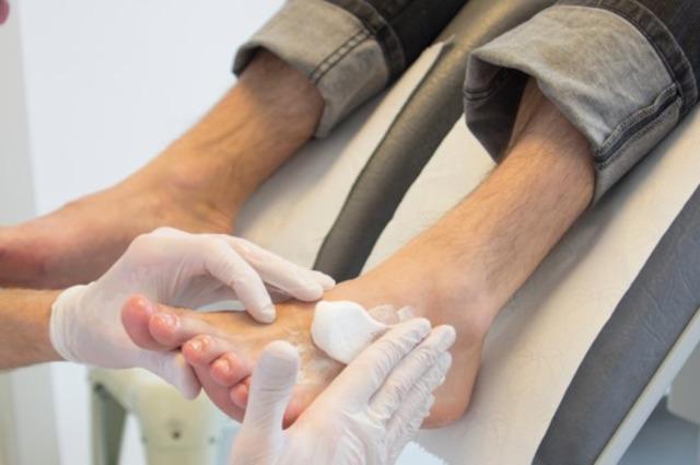 En person får fodbehandling med håndtering af fødderne og anvendelse af creme i en klinik.