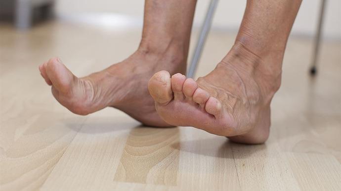 Toes and feet of a person resting on a wooden floor, showcasing skin texture and natural posture.
