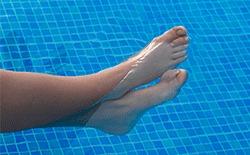 Toes der stikker op af vandet i en swimmingpool med blå fliser.