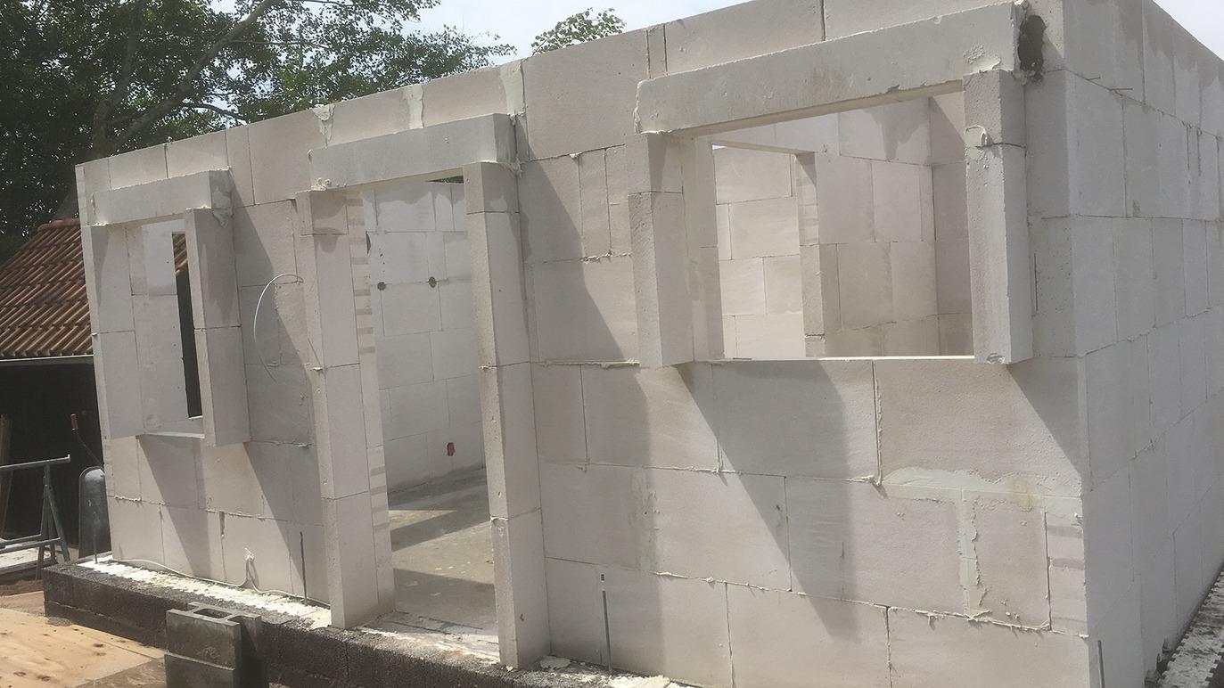 Bygning af hus med hvide blokke, der viser vægge og vinduesåbninger under konstruktion.