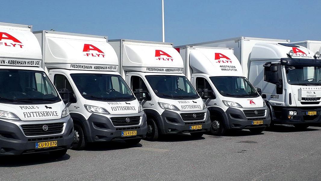 Flere flyttevogne parkeret på en vej, alle med A-Flyt logoet synligt på siden.
