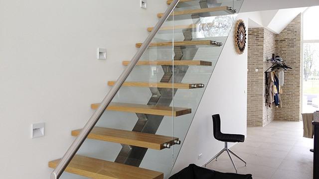 Moderne trappe med glas og trætrin i et lyst rum med minimalistisk indretning.