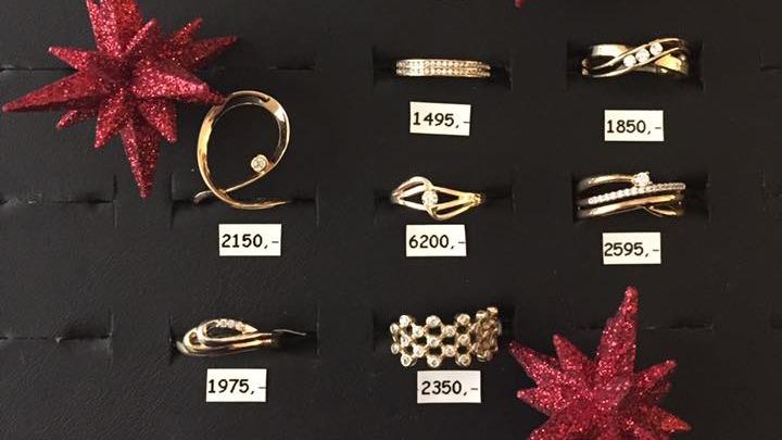 Billede af smukke guld- og diamantringe præsenteret på en sort baggrund med røde stjerner.