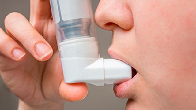 En person bruger en inhalator til at tage medicin mod astma.