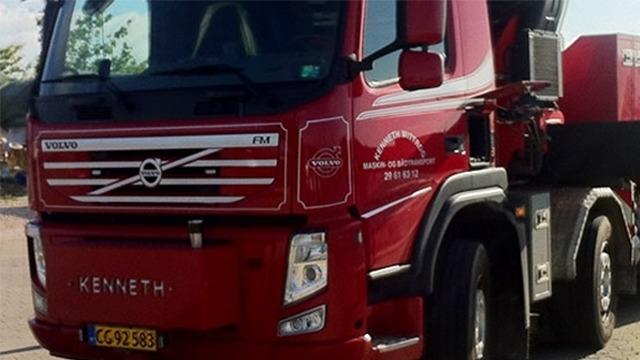 Rød Volvo lastbil med navnet Kenneth og en kran på ladet, parkeret på en byggeplads.