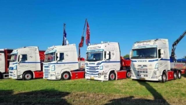 Tre store lastbiler parkeret på en græsplæne under en klar blå himmel.