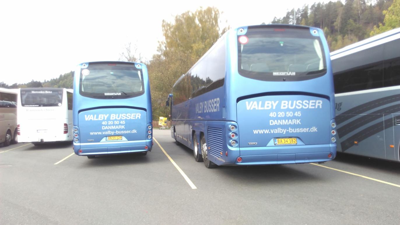 To busser parkeret på en parkeringsplads med Valby Busser logo og blå farve.