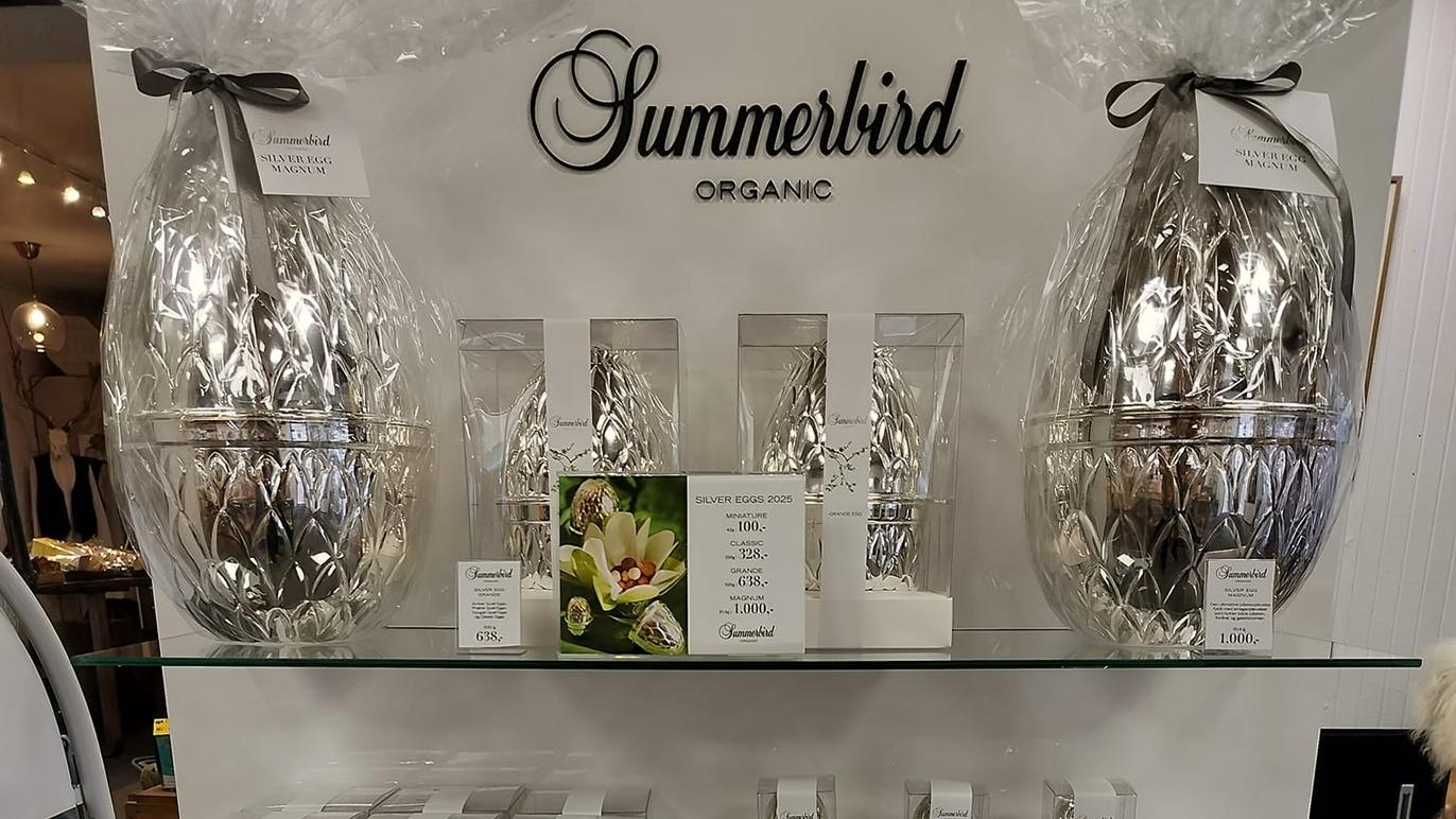 Hylder med Summerbird Organic produkter, herunder elegante krukker og parfumer i smuk indpakning.