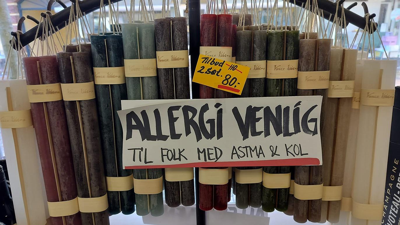 Hyldest med allergivenlige stearinlys i forskellige farver, til salg med skilt om astma og kol.