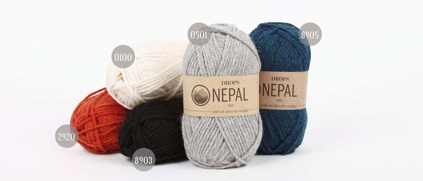 Fem garnnøgler i forskellige farver med etiketter fra Nepal, herunder rød, sort, grå, hvid og blå.