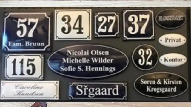 Skilt med navne og numre, herunder Fam. Bruun, Nicolai Olsen, Michelle Wilder og Sørgaard.