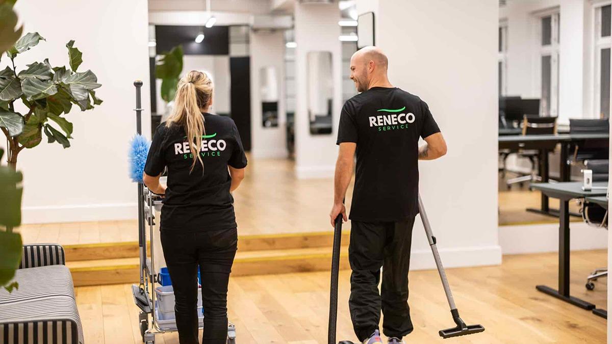 To personer i sorte RITHECO T-shirts, der rengør et kontor med en rengøringsvogn og udstyr.