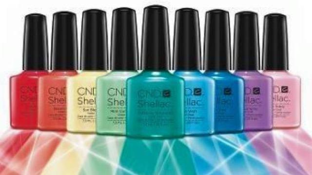 Farverig samling af CND Shellac neglelakflasker i forskellige nuancer på en glitrende baggrund.