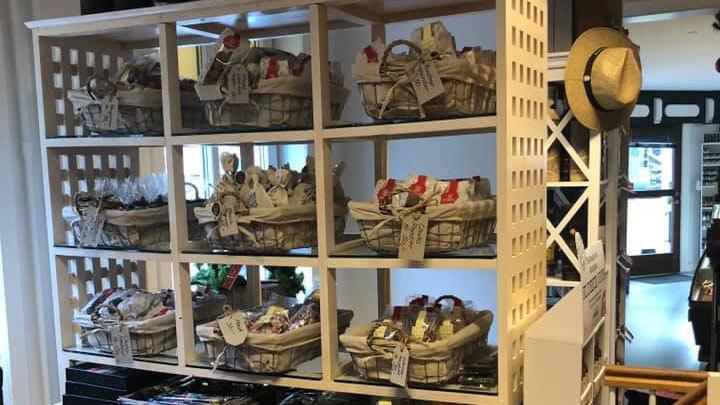 En hylde med kurve fyldt med gaver og produkter, præsenteret i en butik.