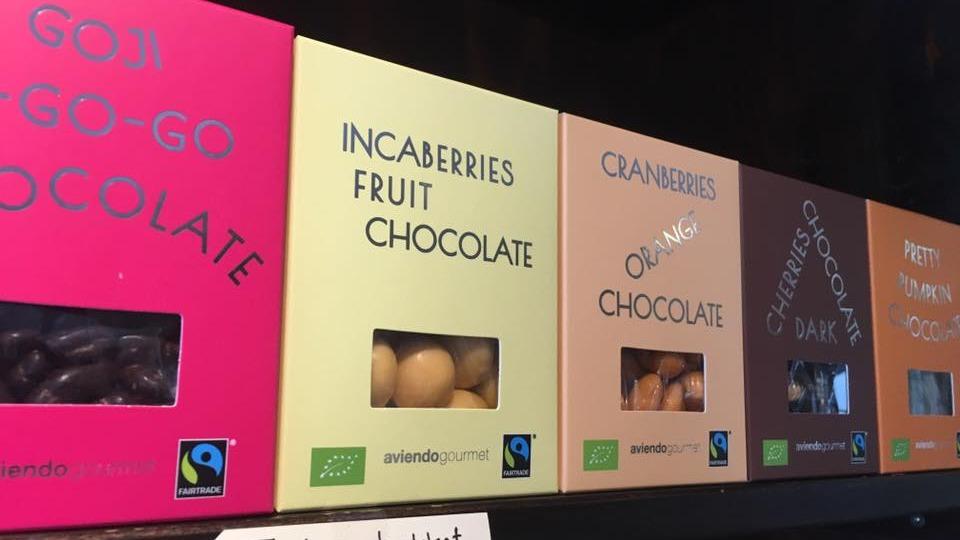 Æsker med forskellige typer chokolade, herunder incaberries, tranebær og mørk chokolade, præsenteret på en hylde.