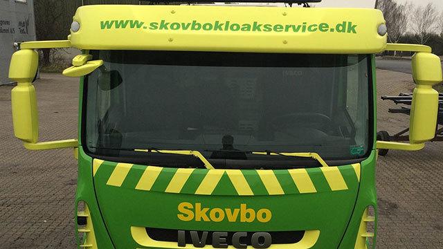 Grøn lastbil fra Skovbo Kloakservice med tydelig logo og webadresse på fronten.