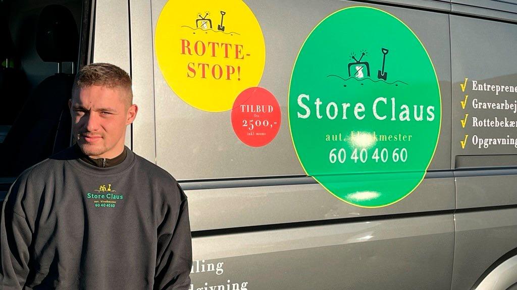 En mand står ved siden af en grå varevogn med reklamer for Store Claus og skadedyrsbekæmpelse.