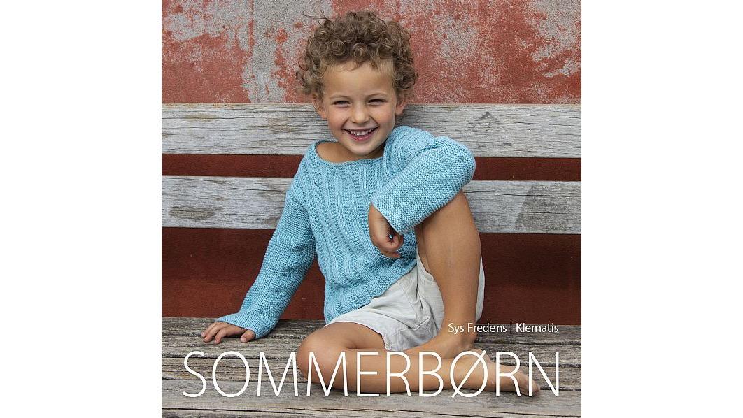 En glad dreng sidder på en bænk iført en lys blå striktrøje og shorts, med et smil på læben.