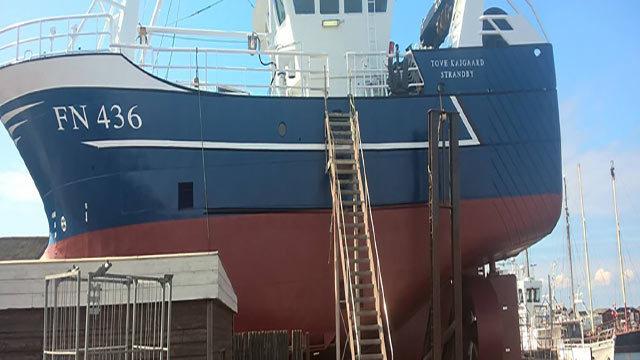 Fiskebåd FN 436 ligger ved kajen med en stige op til dækket og andre både i baggrunden.
